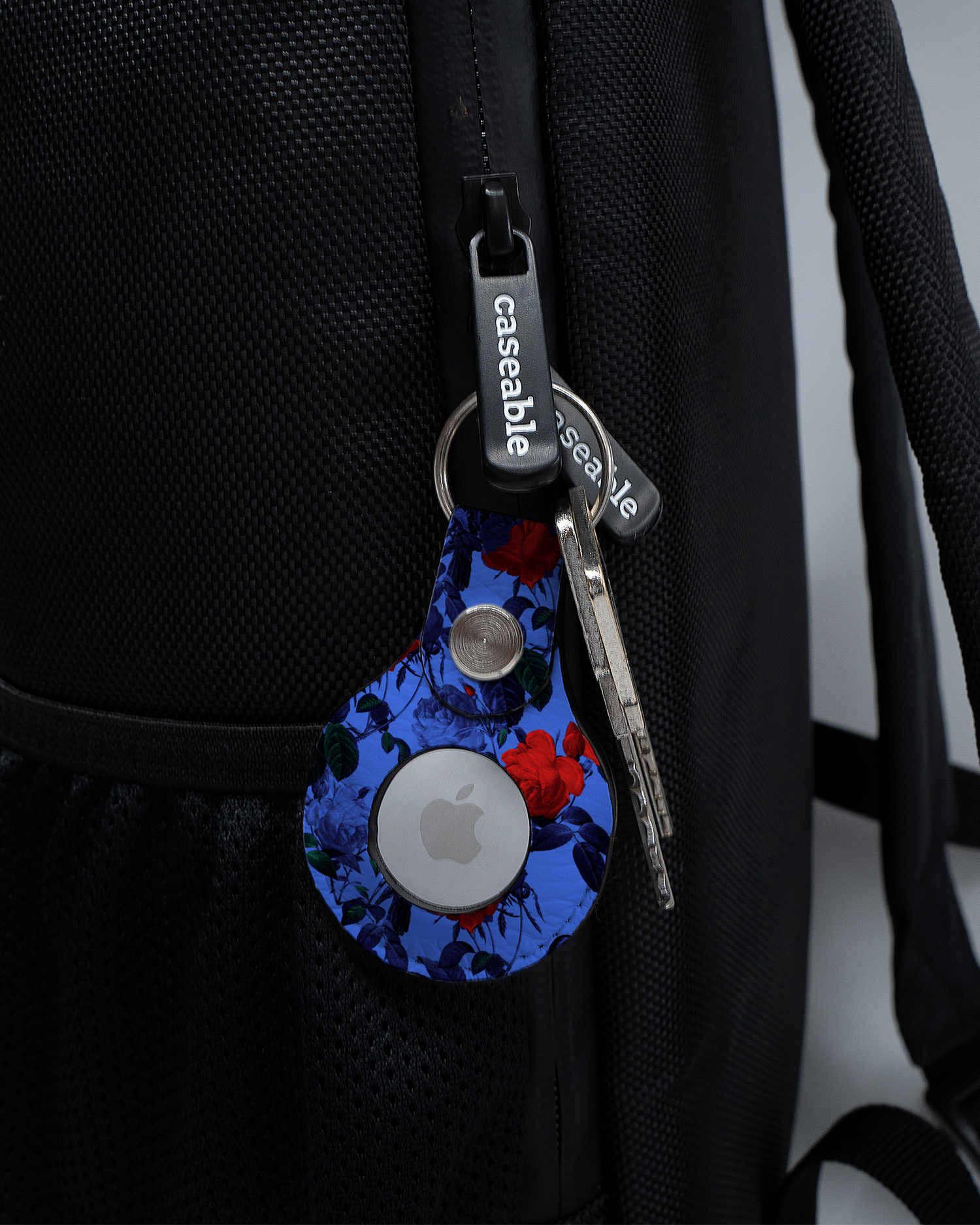 AirTag Holder with design Roses And Ravens attached to a bag
