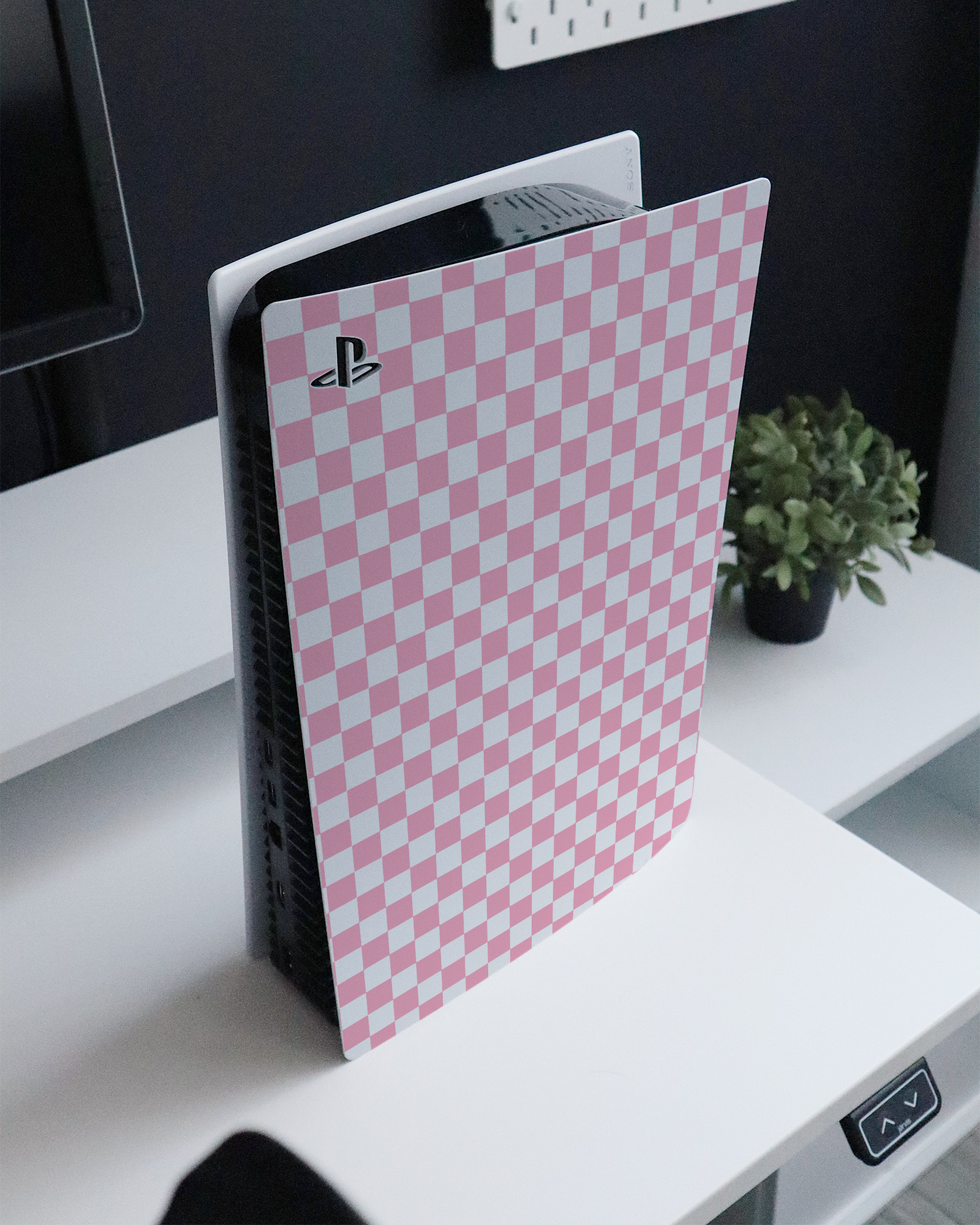 Pink Checkerboard Console Skin for Sony PlayStation 5 Digital Edition standing on a sideboard 