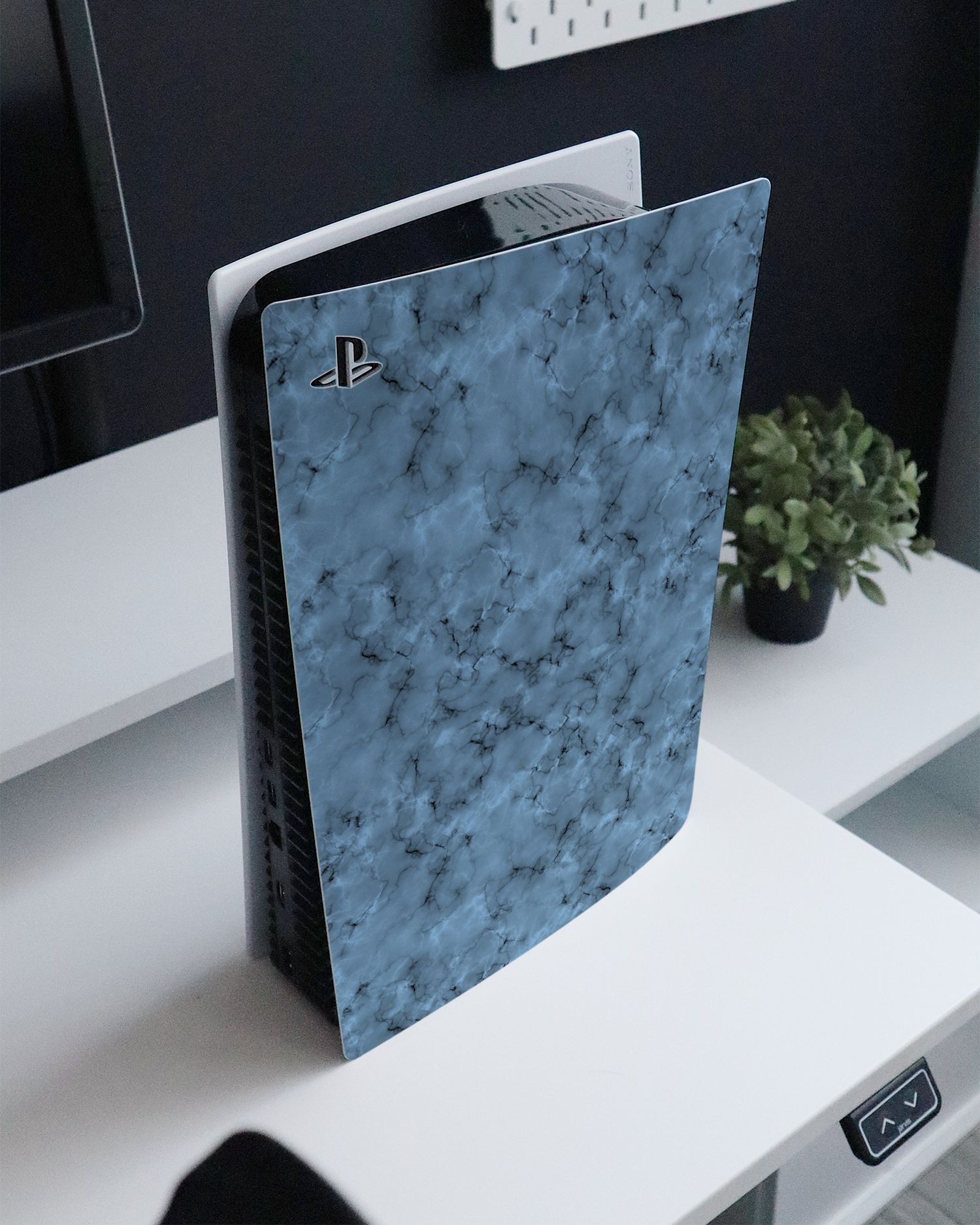 Blue Marble Console Skin for Sony PlayStation 5 standing on a sideboard 