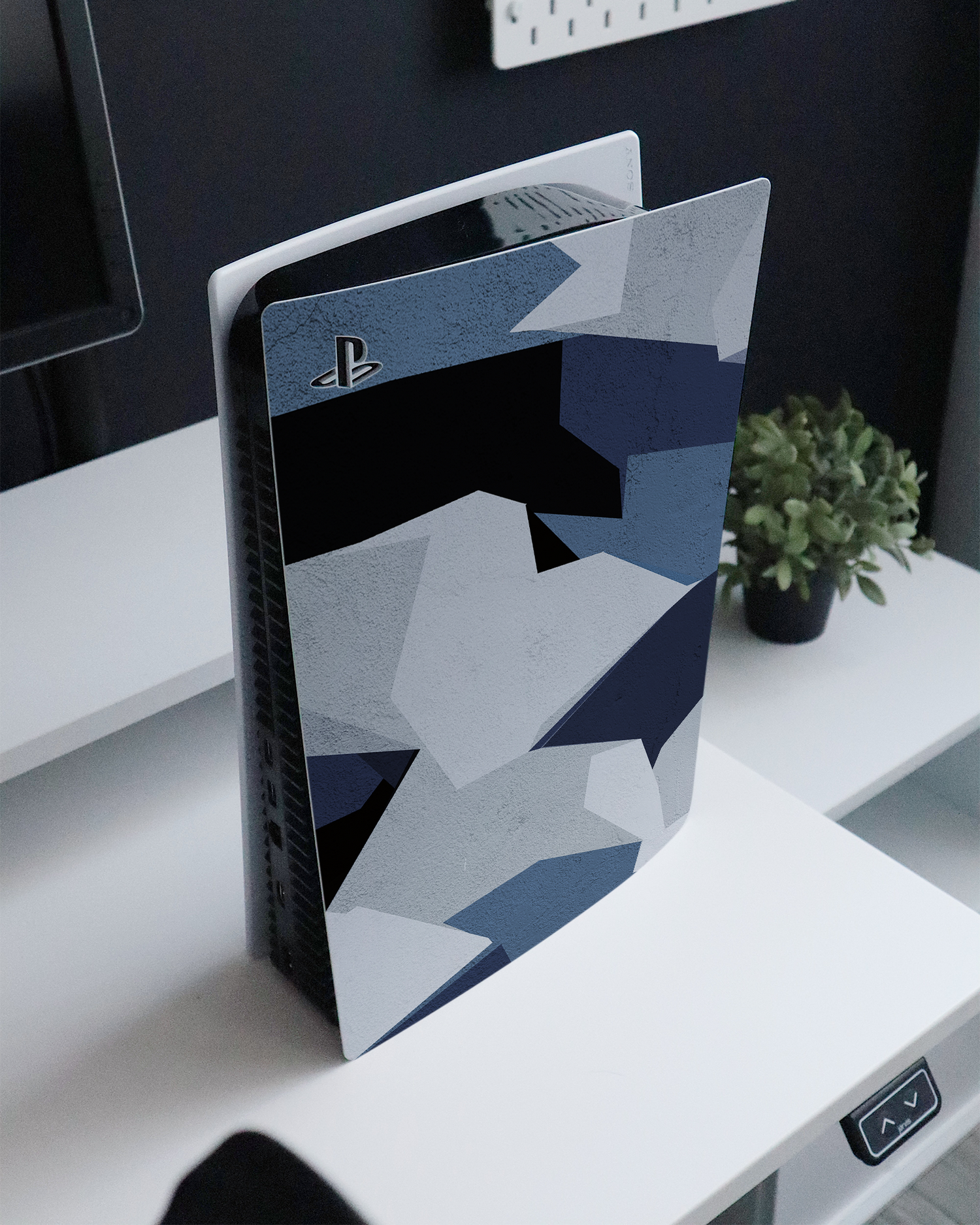 Geometric Camo Blue Console Skin for Sony PlayStation 5 standing on a sideboard 