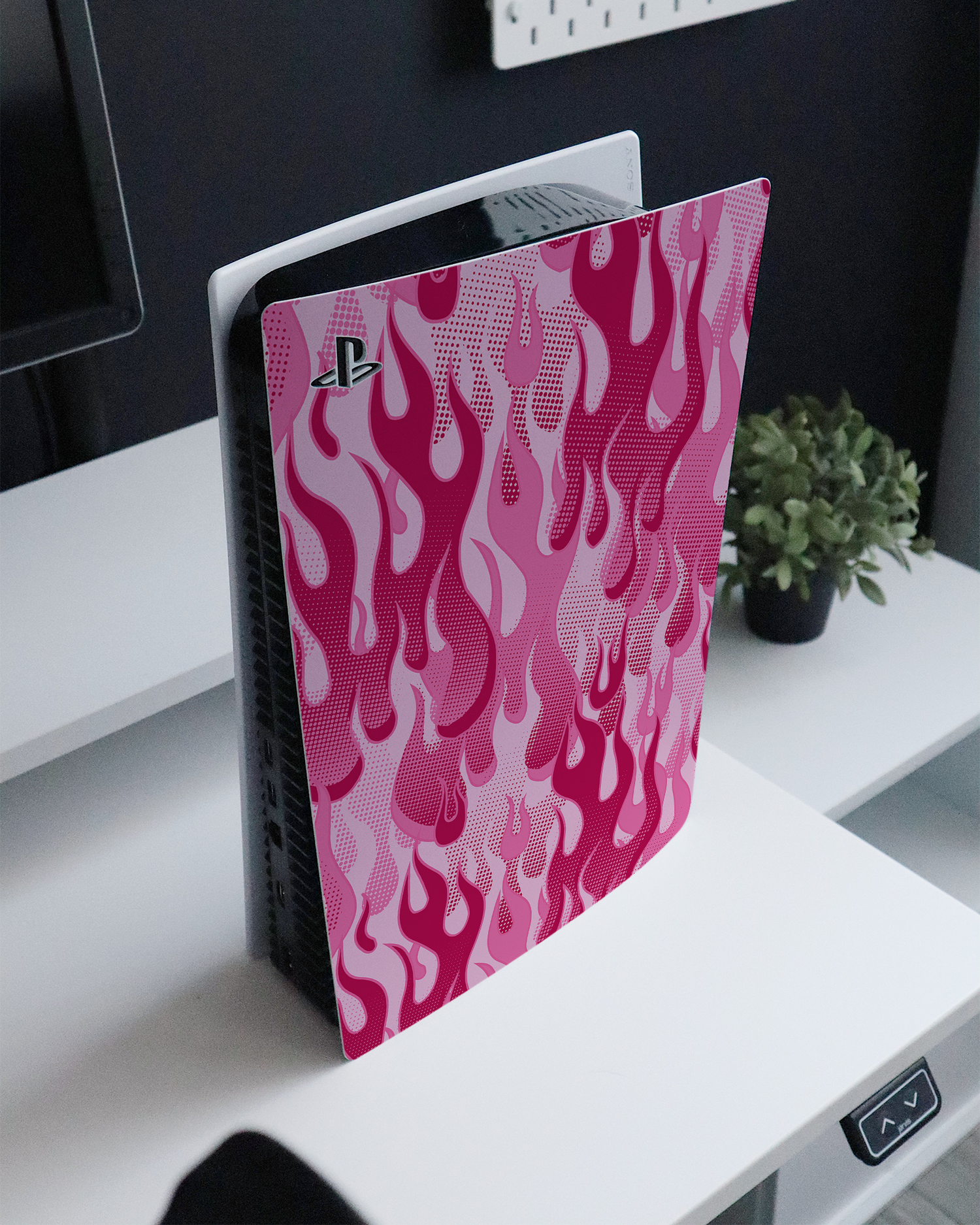 Pink Flames Console Skin for Sony PlayStation 5 standing on a sideboard 