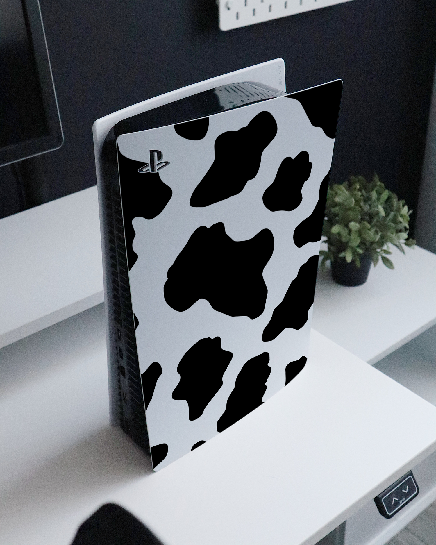Cow Print 2 Console Skin for Sony PlayStation 5 standing on a sideboard 